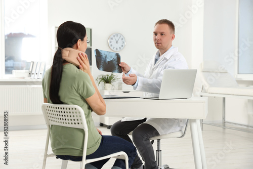 Doctor with neck MRI image consulting patient in clinic