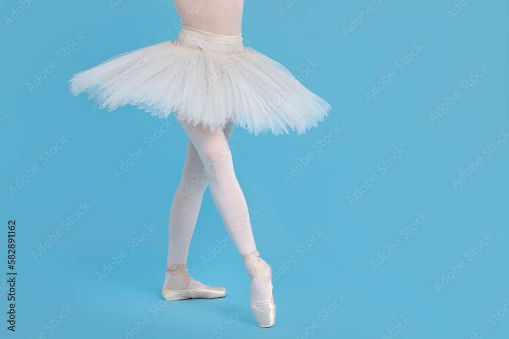 Young ballerina in pointe shoes practicing dance moves on light blue background, closeup. Space for text Young ballerina in pointe shoes practicing dance moves on light blue background, closeup. Space for text