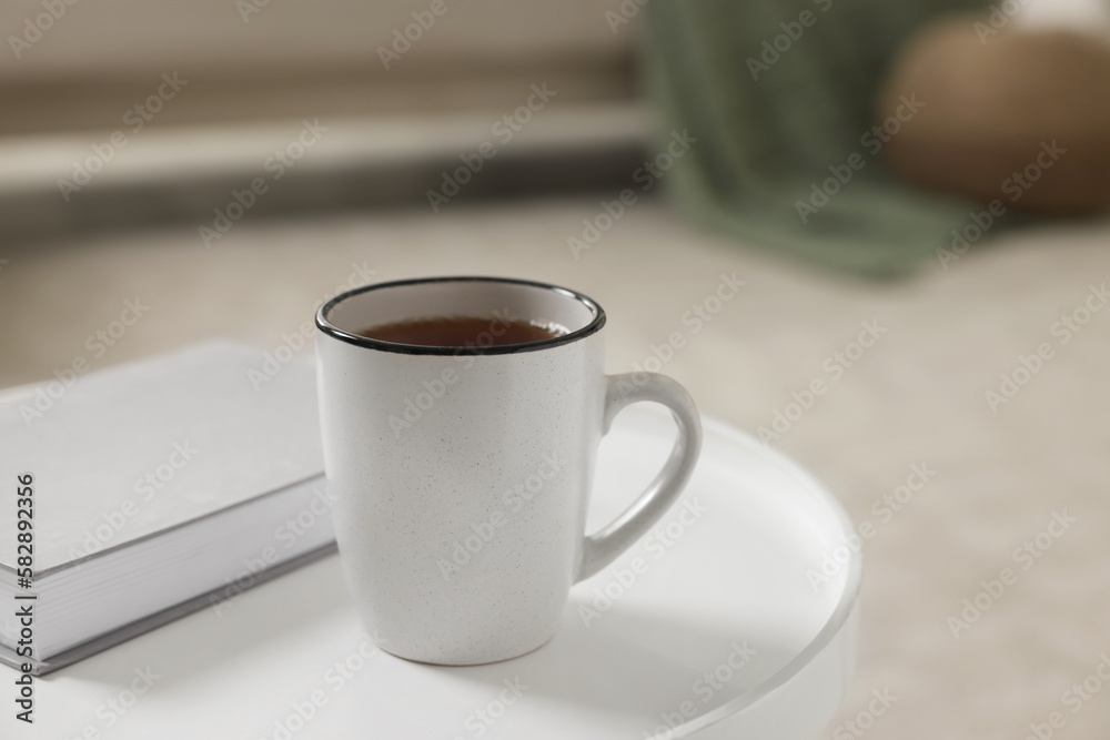 Ceramic mug of tea and book on white table indoors. Mockup for design Ceramic mug of tea and book on white table indoors. Mockup for design