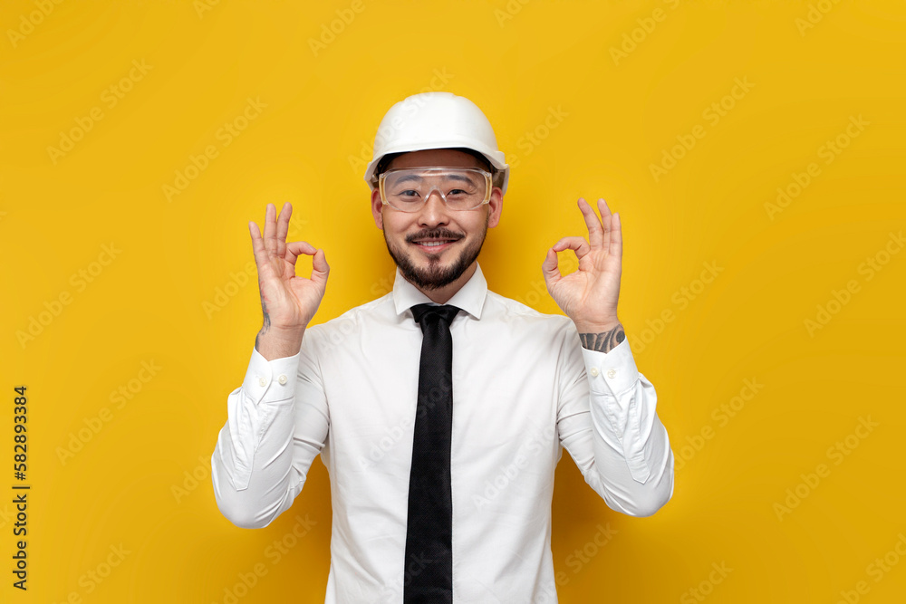 asian foreman in shirt with tie showing ok with hands over yellow isolated background, korean civil engineer