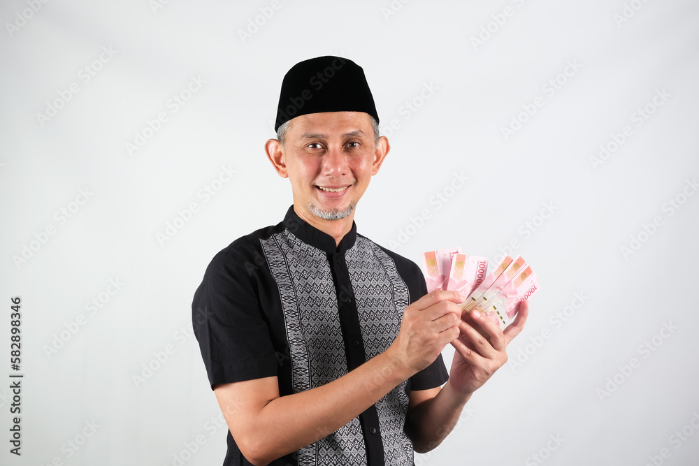 Portrait of Asian Moslem Man looking happy with holding lots of money in hand
Portrait of Asian Moslem Man looking happy with holding lots of money in hand