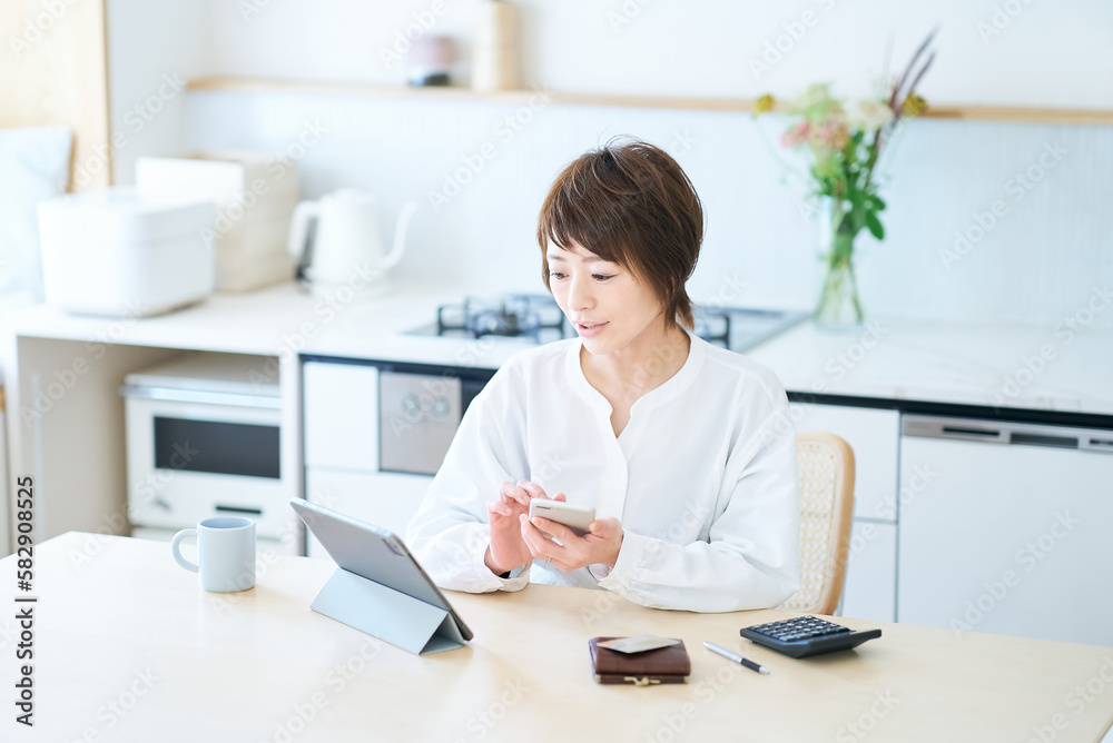 部屋でスマートフォンを操作する女性 部屋でスマートフォンを操作する女性