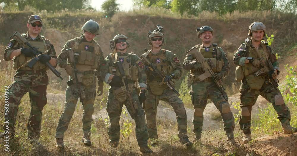 Happy smiling men and woman in camouflage chatting after successful game of war Father's day,slow motion soldiers hugging embracing posing to camera friendship team togetherness