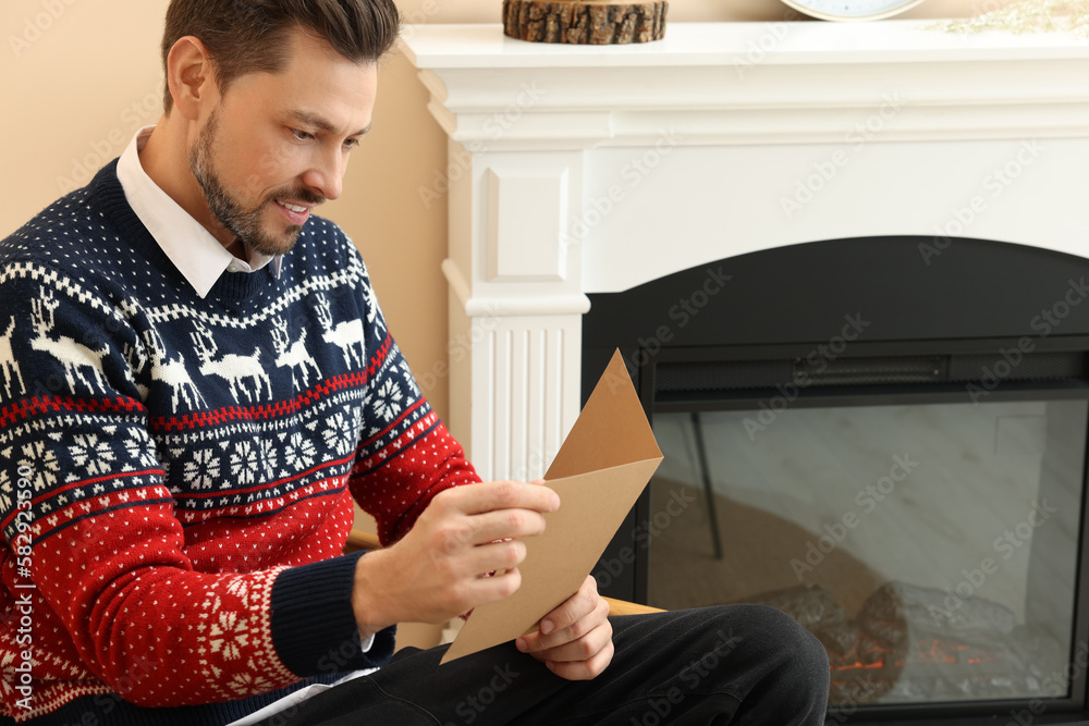 Happy man reading greeting card in living room Happy man reading greeting card in living room