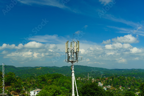 Communication tower against the background of sky and green plants