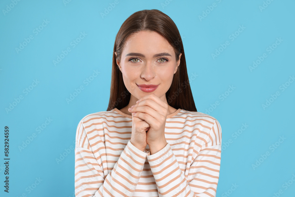 Woman with clasped hands praying on turquoise background Woman with clasped hands praying on turquoise background