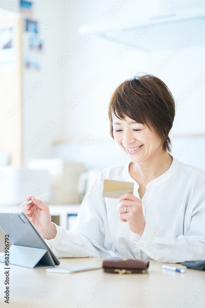 カードを持ってタブレットPCを操作する女性