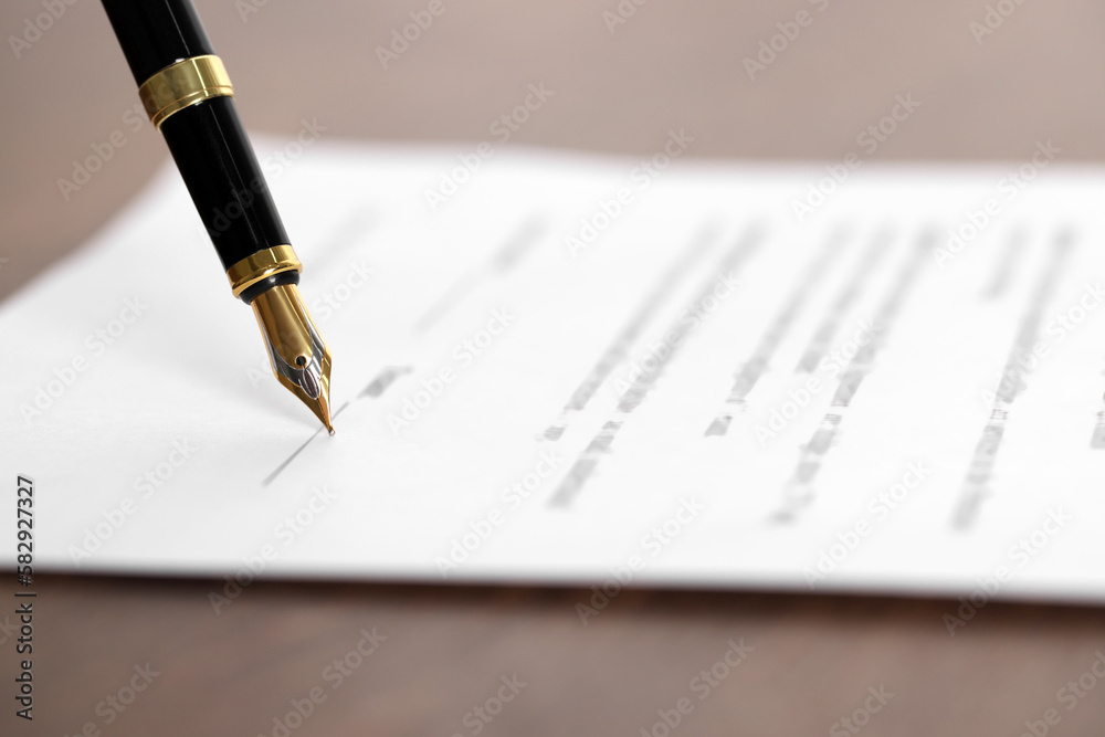 Writing on document with fountain pen at wooden table, closeup. Notary contract Writing on document with fountain pen at wooden table, closeup. Notary contract