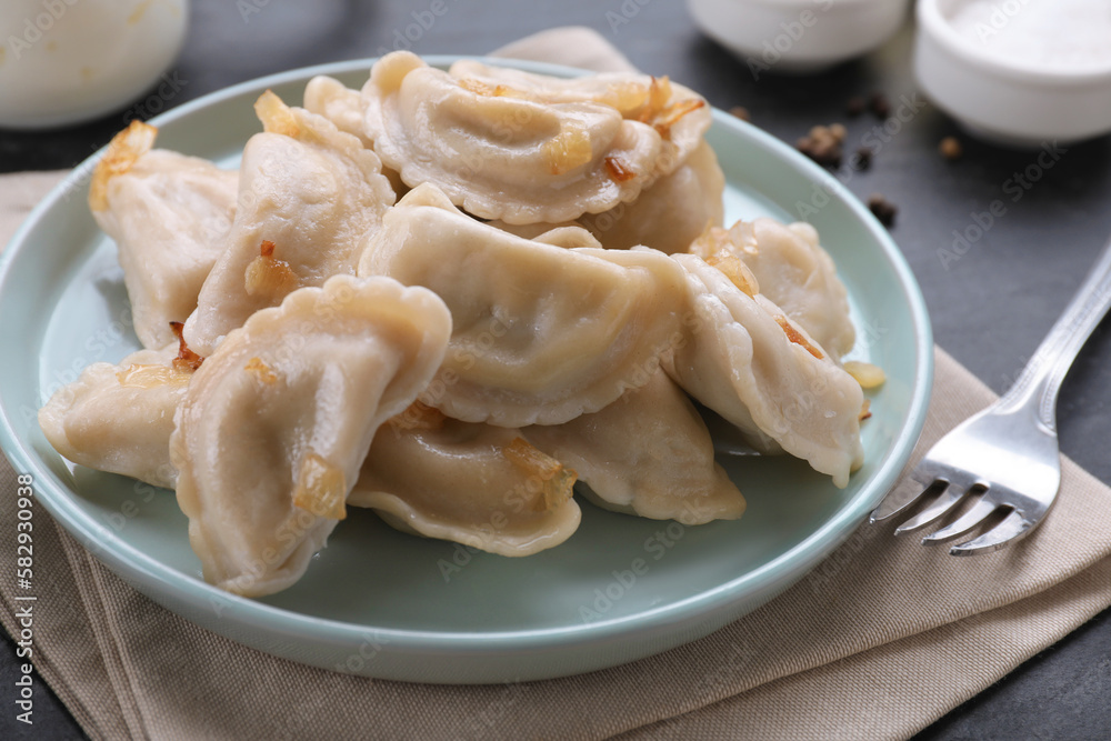 Delicious dumplings (varenyky) with potatoes and onion served on black table, closeup Delicious dumplings (varenyky) with potatoes and onion served on black table, closeup
