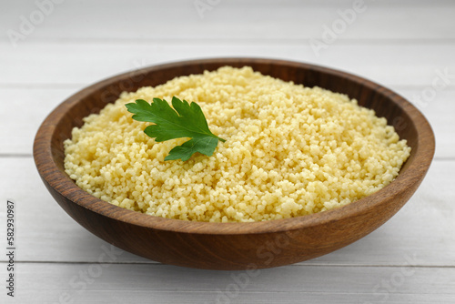 Tasty couscous with parsley on white wooden table, closeup