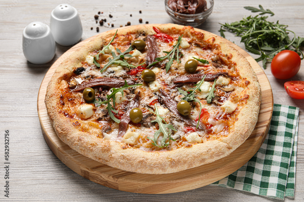 Tasty pizza with anchovies and ingredients on grey wooden table