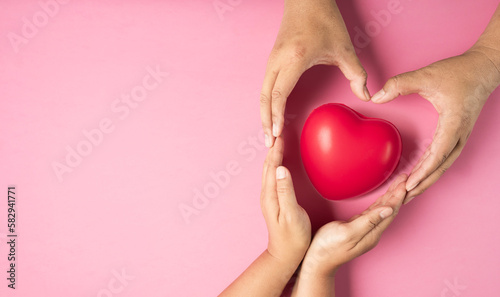 Adult hands made heart symbol on pink background , health care, organ donation, family life insurance, world heart day, world health day, praying concept