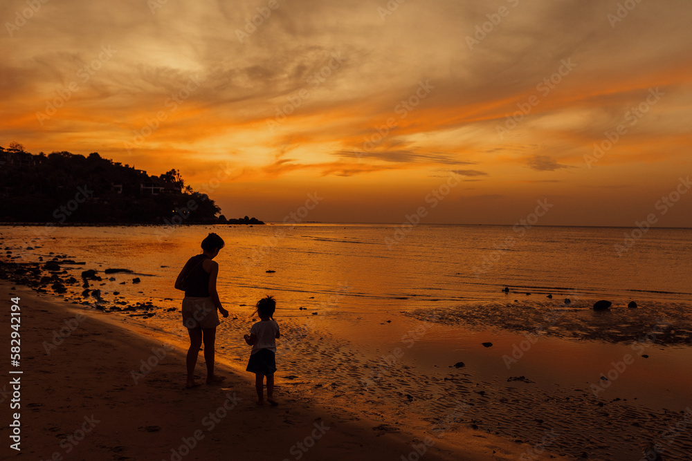 Naklejka premium walking on the beach at sunset