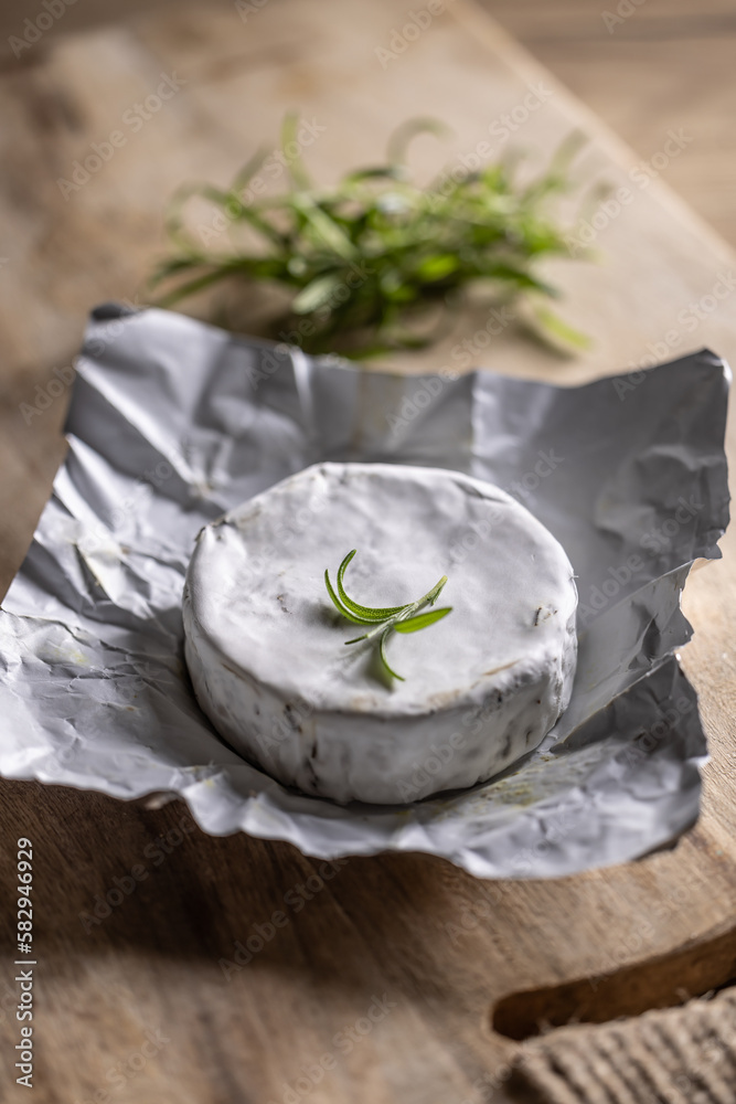 Opened package of brie cheese with a spring of rosemary on top with a