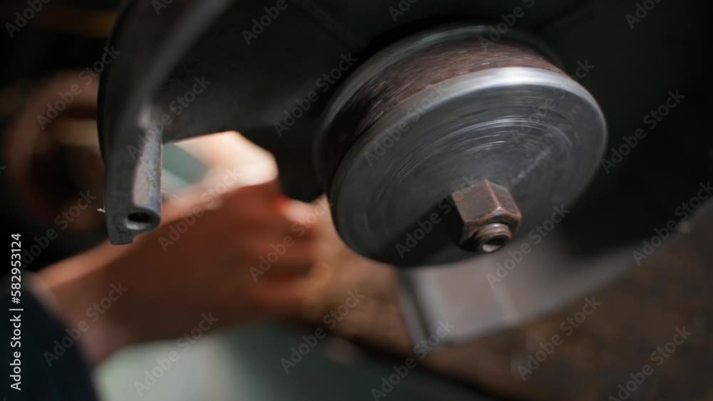 The hand presses the start button of the grinder, the abrasive wheel begins to rotate in the foreground. Worn grinding wheel The hand presses the start button of the grinder, the abrasive wheel begins to rotate in the foreground. Worn grinding wheel