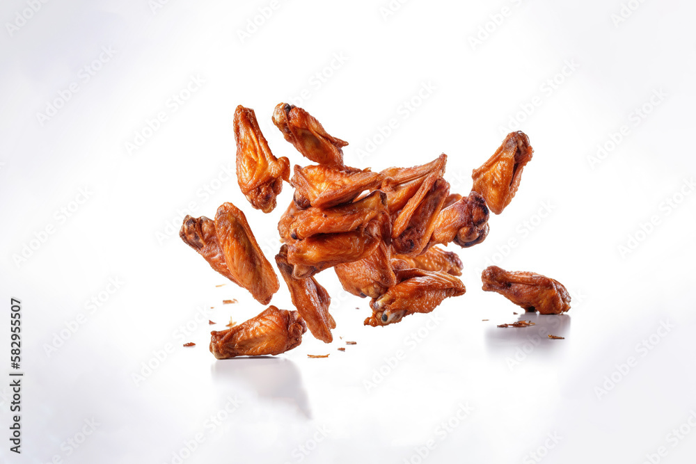 Fototapeta premium Tasty falling fried spicy chicken wings isolated on white background. Created with Generative AI Technology