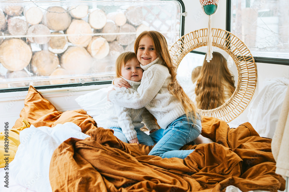 little red haired cute siblings girls sisters having fun in cosy bed in trailer mobile home or recreational vehicle during family local travel