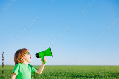 Happy child shouting through loudspeaker against blue summer sky