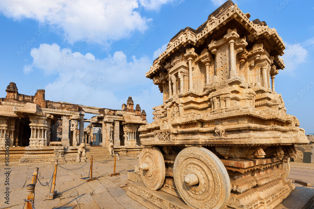 Ancient stone chariot at Vijaya Vittala temple with other architecture ruins at Hampi Karnataka, India