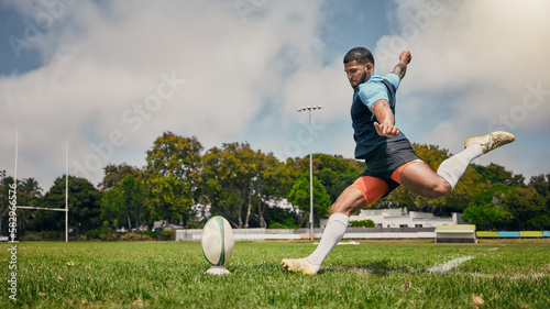 Rugby, action and man kicking ball to score goal on field at game, match or practice workout. Sports, fitness and motion, player running to kick at poles on grass with energy and skill in team sport.