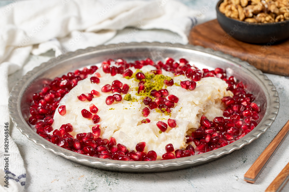 Gullac dessert. Ramadan dessert. Gullac decorated with pomegranate and pistachio in copper plate on gray background. Symbolic food