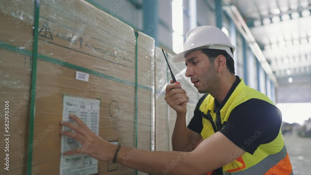 Professional caucasian elegant young engineer holding a radio communication talking with colleague to inspect the products in the factory Professional caucasian elegant young engineer holding a radio communication talking with colleague to inspect the products in the factory