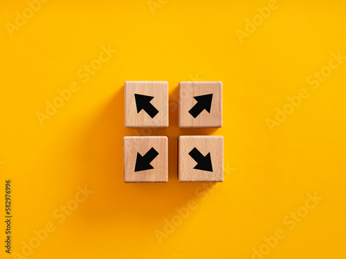 Arrow icons on wooden cubes moving to opposite directions. photo