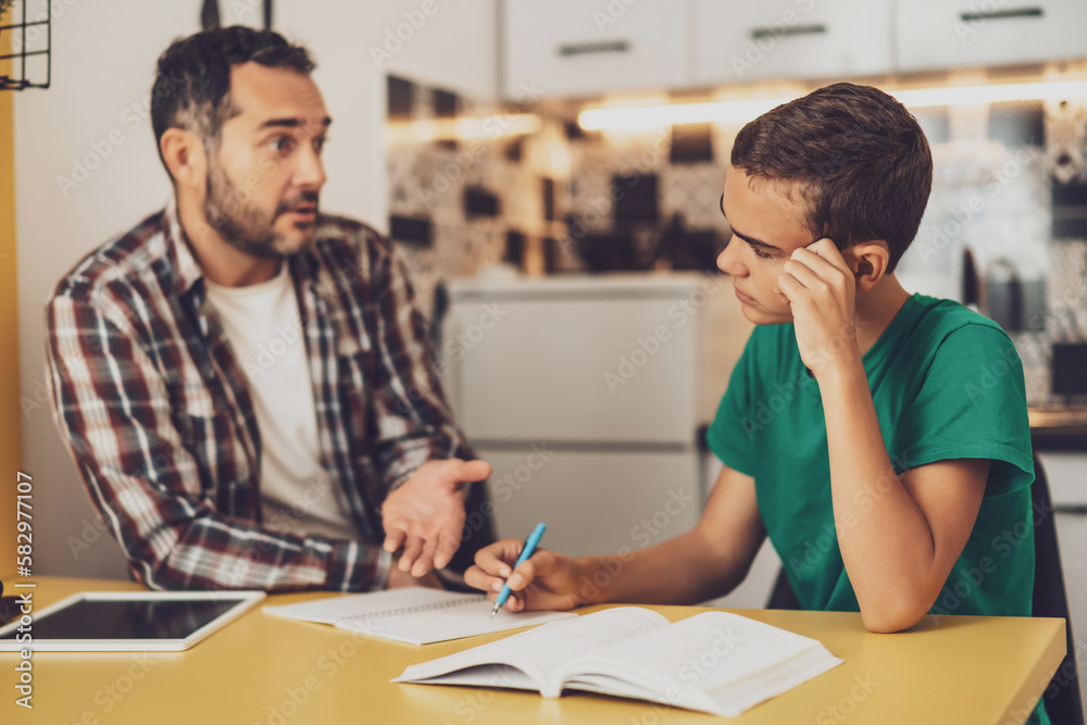 Father is helping his son with learning. They are doing homework together. Father is helping his son with learning. They are doing homework together.