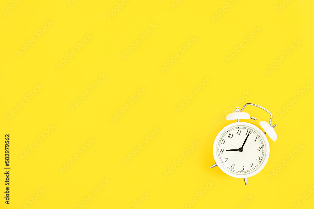 White alarm clock on a yellow background, flat lay. White alarm clock on a yellow background, flat lay.