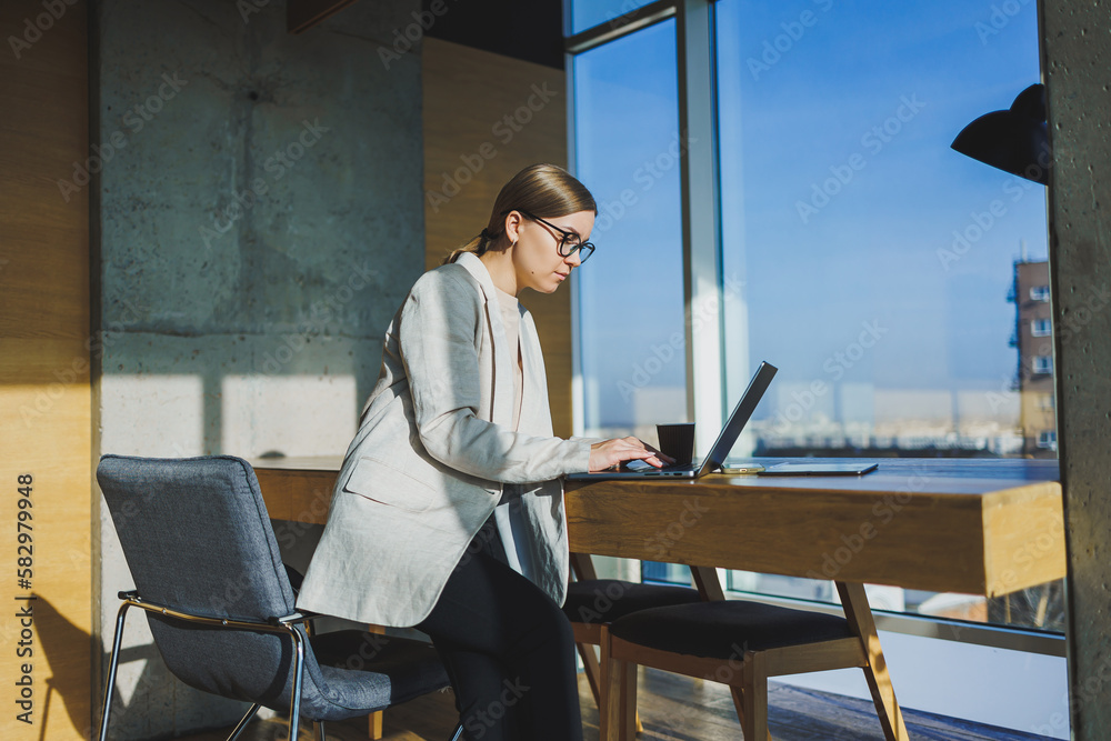 Office work, attractive young female manager working in office, standing in bright workspace using modern laptop computer, young woman drinking delicious coffee Office work, attractive young female manager working in office, standing in bright workspace using modern laptop computer, young woman drinking delicious coffee