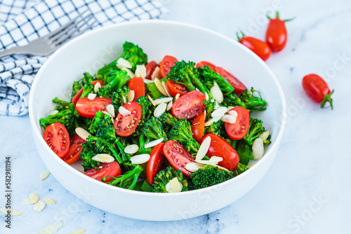 Broccoli salad with cherry tomatoes and almonds in white bowl. Vegan detox recipe.