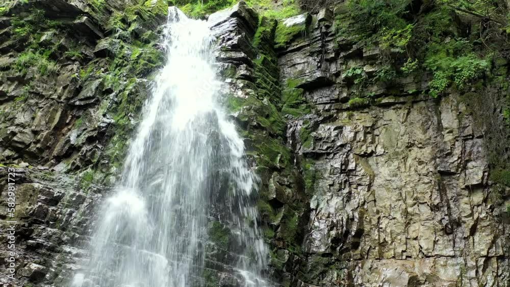 Mountain waterfall bottom view with a green forest on the top, aerial view Mountain waterfall bottom view with a green forest on the top, aerial view