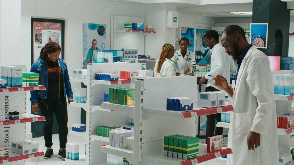 Pharmacy employee showing medicaments to woman, recommending healthcare products and pills. Young customer talking to pharmacist about medical treatment, pharmaceutics. Tripod shot. Pharmacy employee showing medicaments to woman, recommending healthcare products and pills. Young customer talking to pharmacist about medical treatment, pharmaceutics. Tripod shot.