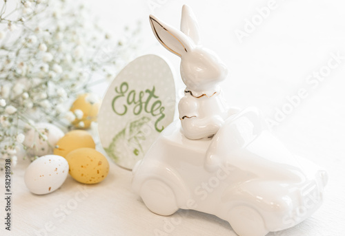 Easter background with a ceramic hare in the car and eggs on a white background,