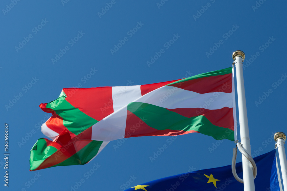 Le drapeau basque qui flotte dans le vent devant le drapeau européen