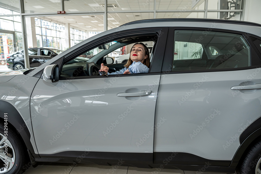 Fototapeta premium pretty smile young woman client inside at new modern auto and holding key, purcase concept