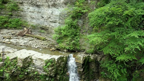 Mountain waterfall bottom view with a green forest on the top, aerial view  photo