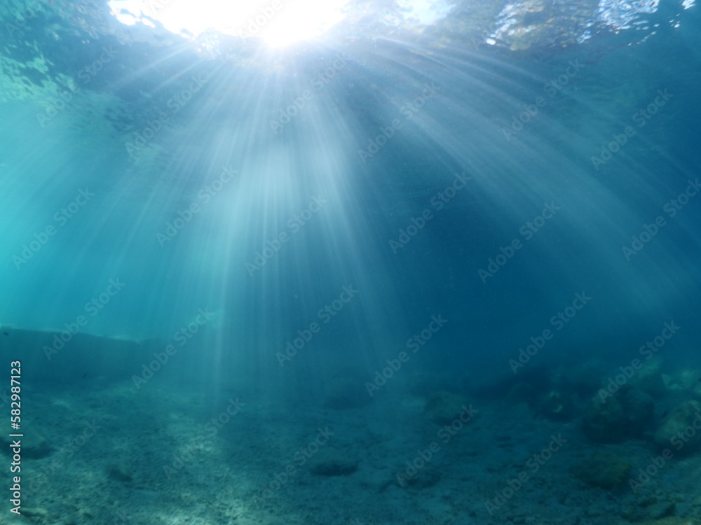 Naklejka premium sun rays sun beam and sun shine on rocks underwater