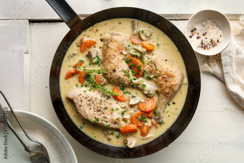 French chicken fricassee. saute chicken slow cooked in a creamy white sauce with mushroom and carrot photo