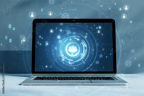 Close up of laptop on desktop with glowing people icons. Creative global structure networking and data exchanges customer connection hologram on blurry background. 3D Rendering.