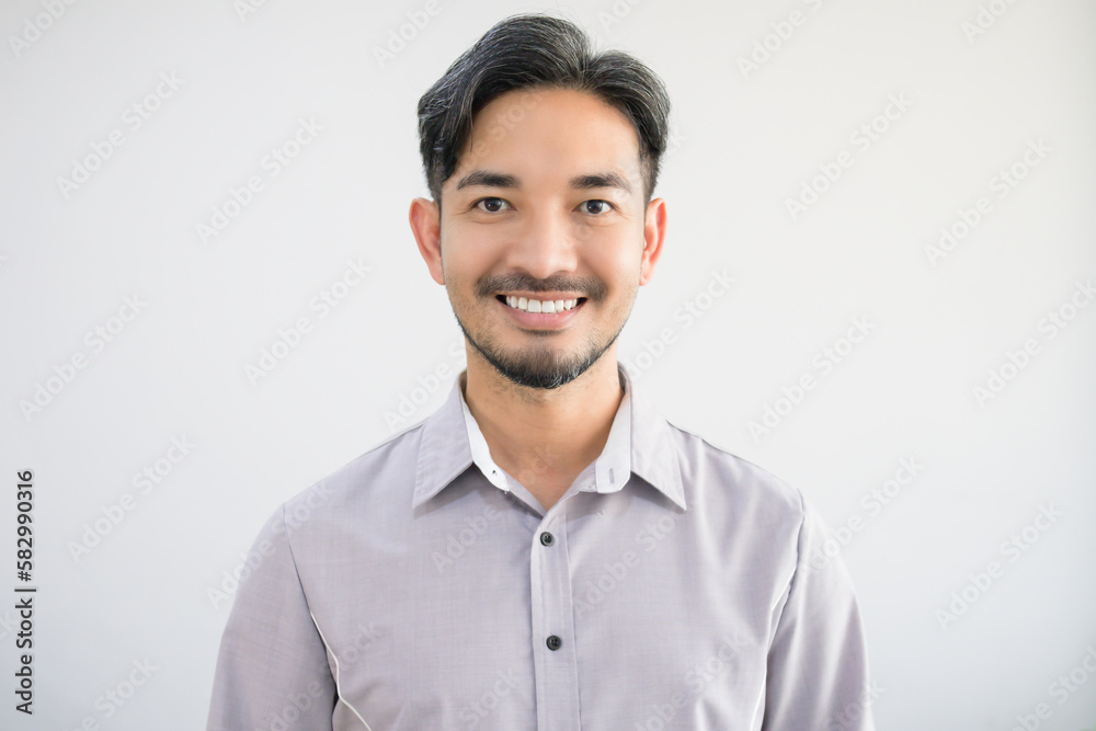 Portrait of a handsome Asian man with a beard in a gray shirt making a smile face. Portrait of a handsome Asian man with a beard in a gray shirt making a smile face.
