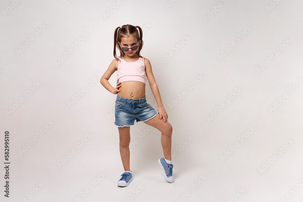 Cute little girl wearing denim shorts and top, white background Stock Photo
