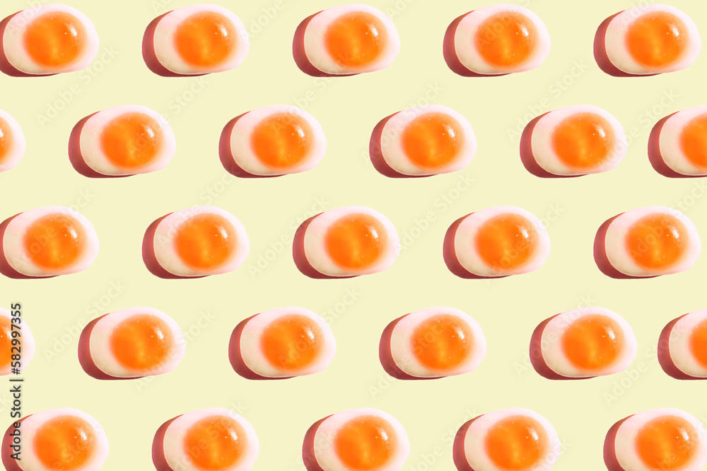 Pattern of egg shaped candy flat laid against yellow background stock