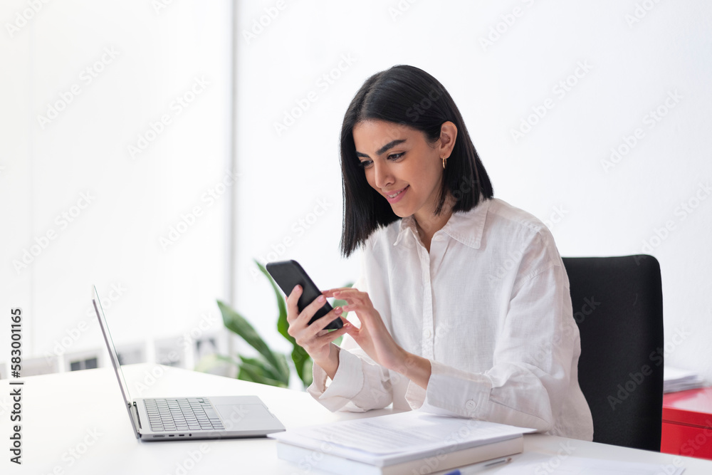 Smiling businesswoman using mobile phone at desk Smiling businesswoman using mobile phone at desk