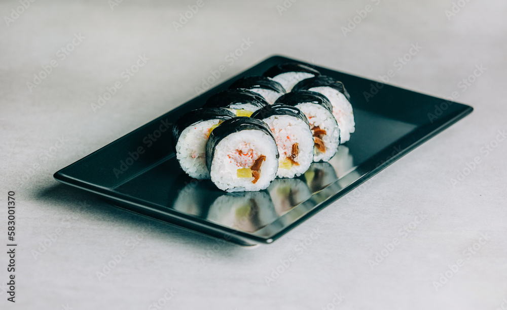 sushi rolls with eel on black plate on gray background