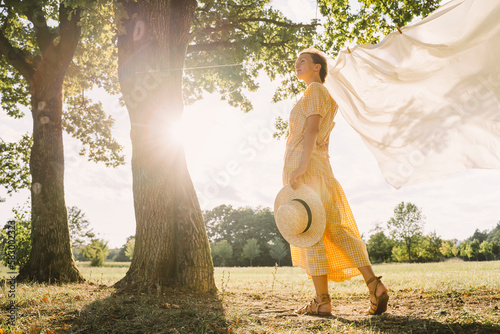 Thoughtful woman standing with hat at park photo