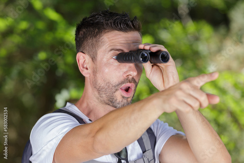 shocked man with binoculars pointing into distance