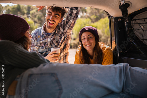 Happy friends taking to woman in trunk of campervan photo