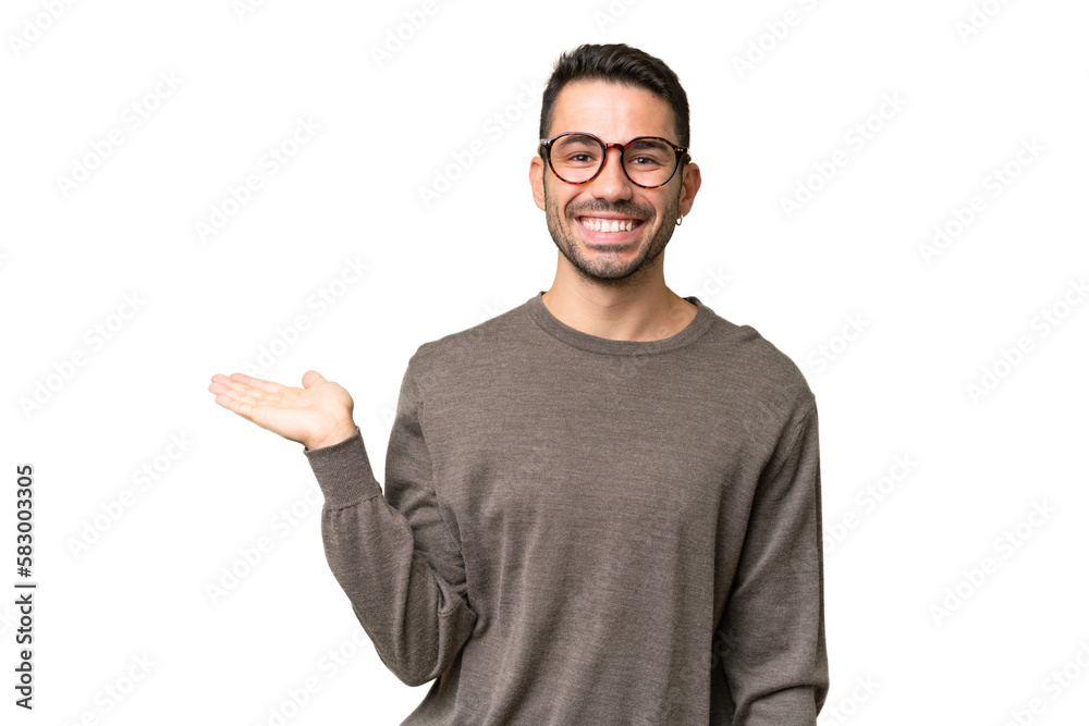 Young handsome caucasian man over isolated background holding copyspace imaginary on the palm to insert an ad