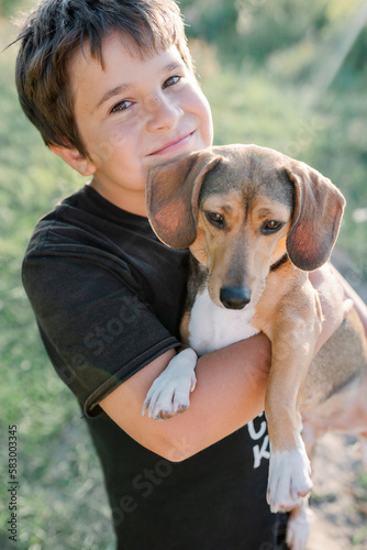 Cute smiling boy carrying brown outbred dog photo